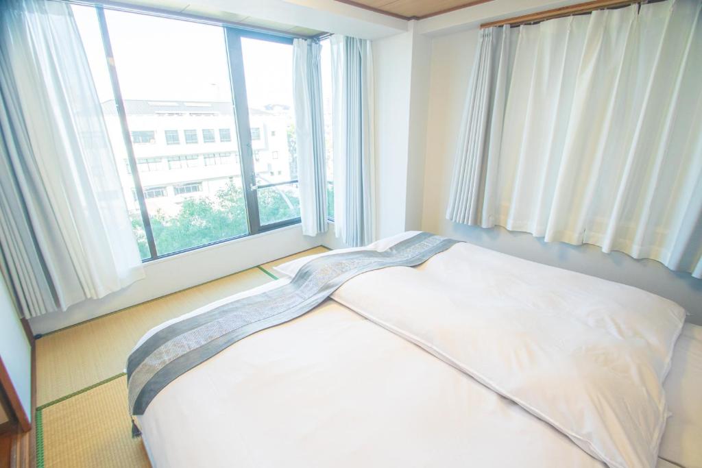 Bett in einem Zimmer mit einem großen Fenster in der Unterkunft AMP FLAT Nishijin 5 in Fukuoka
