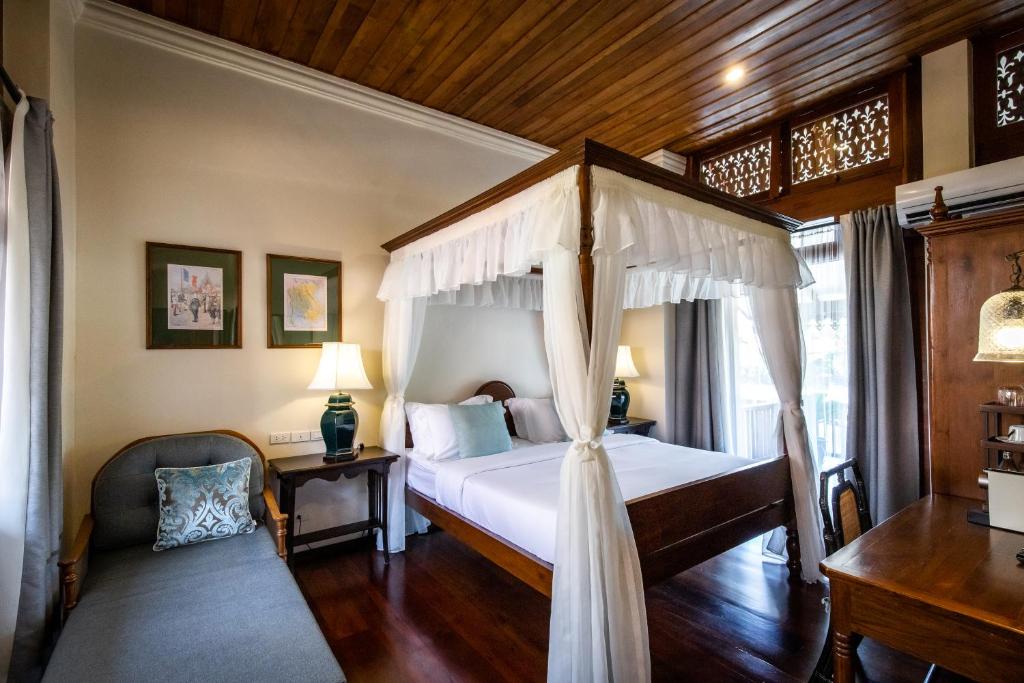 a bedroom with a canopy bed and a chair at Punyashthiti villa in Chanthaburi