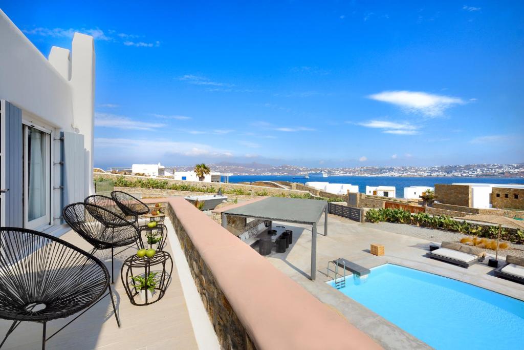 a patio with chairs and a swimming pool on a building at Tohu Villas Mykonos in Ornos