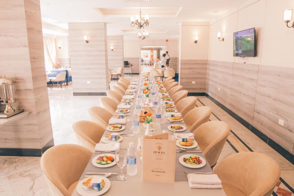 a long dining room with a long table with plates of food at Jewel Green Mountain Hotel in Cairo