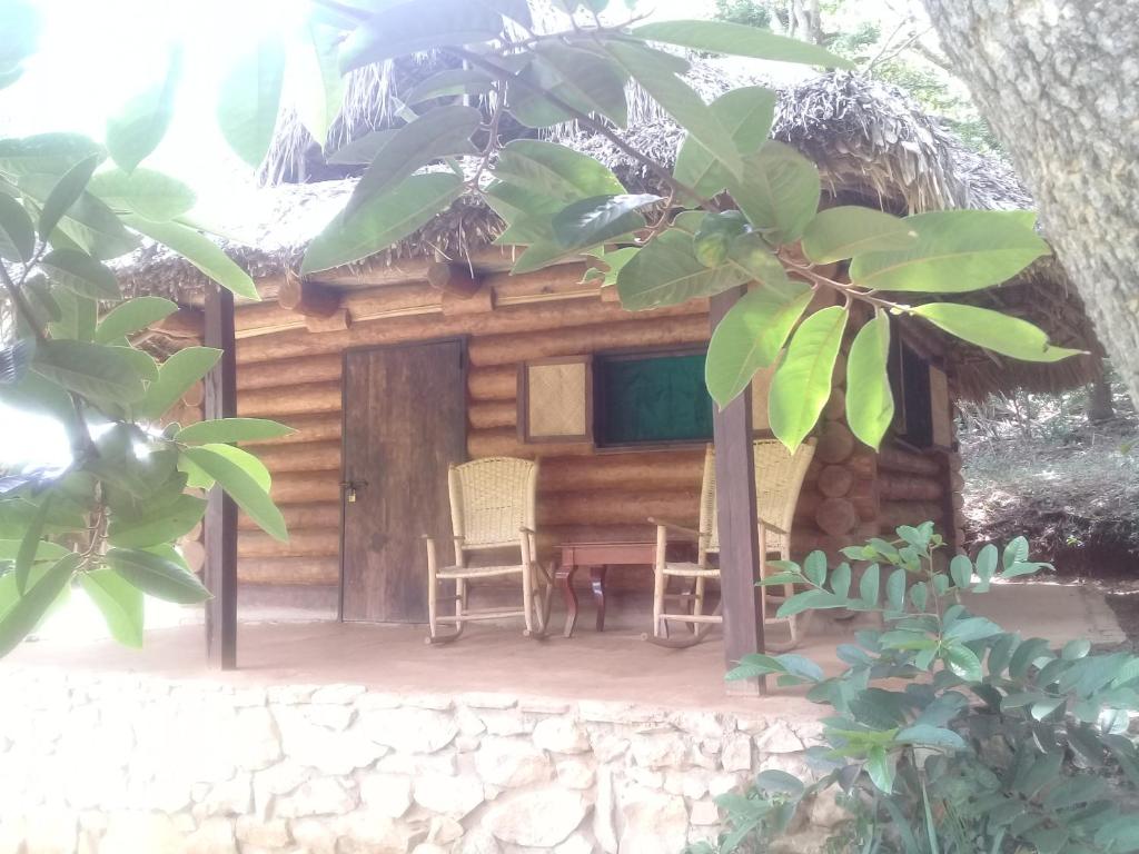 a log cabin with two chairs and a table at Room in Lodge - Sierraverde Huasteca Potosina Cabins Palo De Rosa in Tamasopo