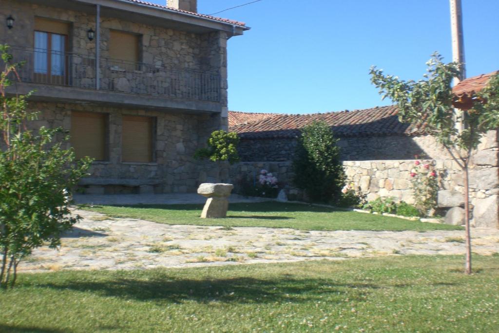 una casa de piedra con un banco en el patio en Casa Rural La Curva, en Barajas de Gredos