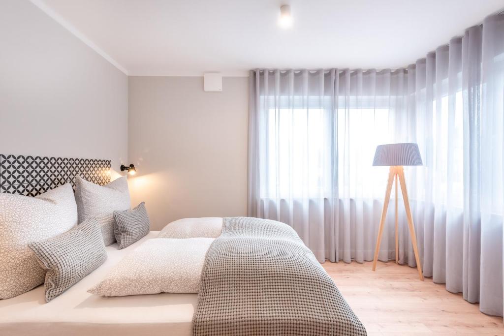 a white bedroom with a bed and a window at The Woodmans Airport Boardinghouse in Düsseldorf