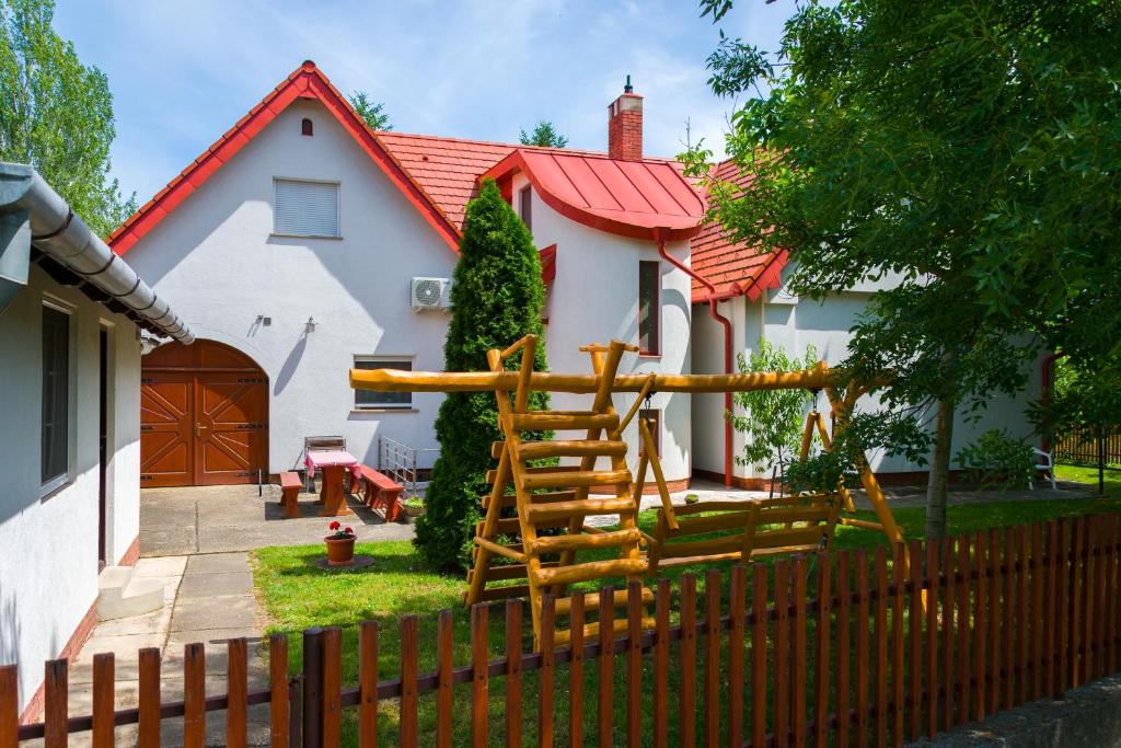 a house with a wooden fence in front of it at Huszár vendégház in Örvényes