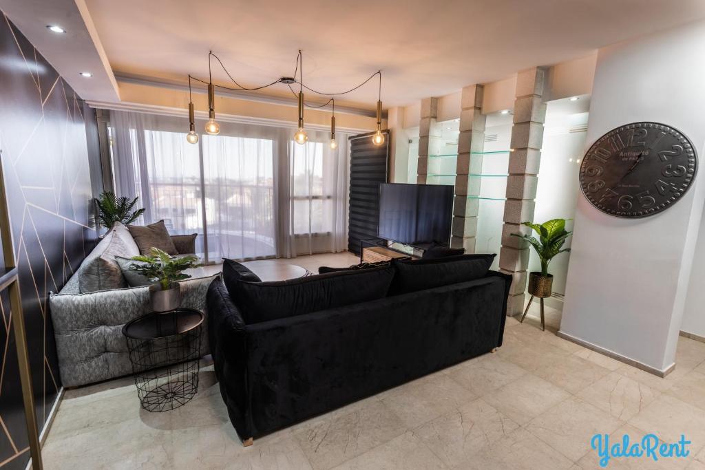 - un salon avec un canapé noir et un réveil dans l'établissement YalaRent Amdar Lux, à Eilat