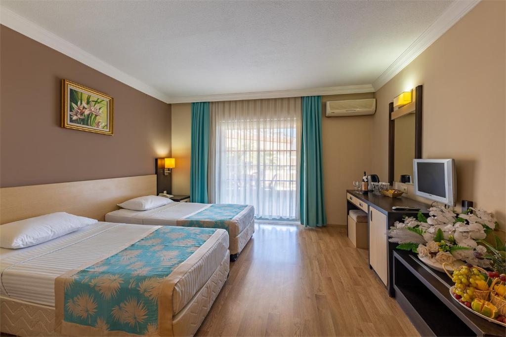 a hotel room with two beds and a television at Viking Nona Beach in Kemer