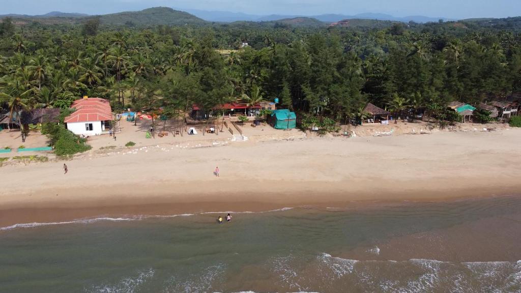 an aerial view of a beach with people in the water at Trippr Gokarna - Beach Hostel in Gokarna