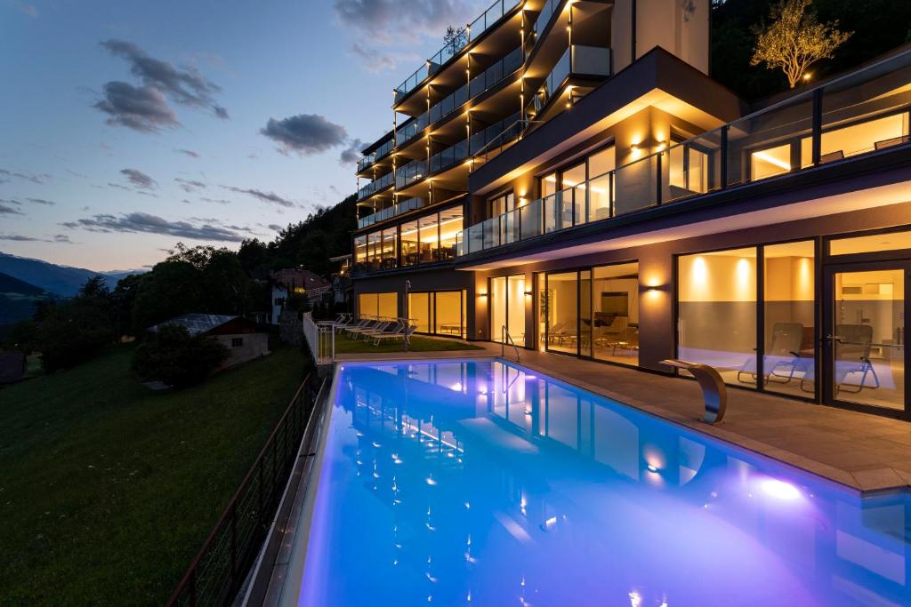 una casa con piscina por la noche en Hotel Lechner en Tirolo