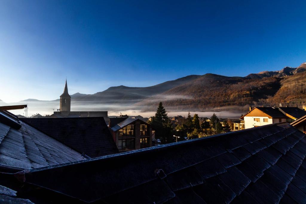 a view from the roof of a town with a misty mountain at Cau d Aneu Duplex en el centro d Esterri d Aneu in Esterri d'Àneu