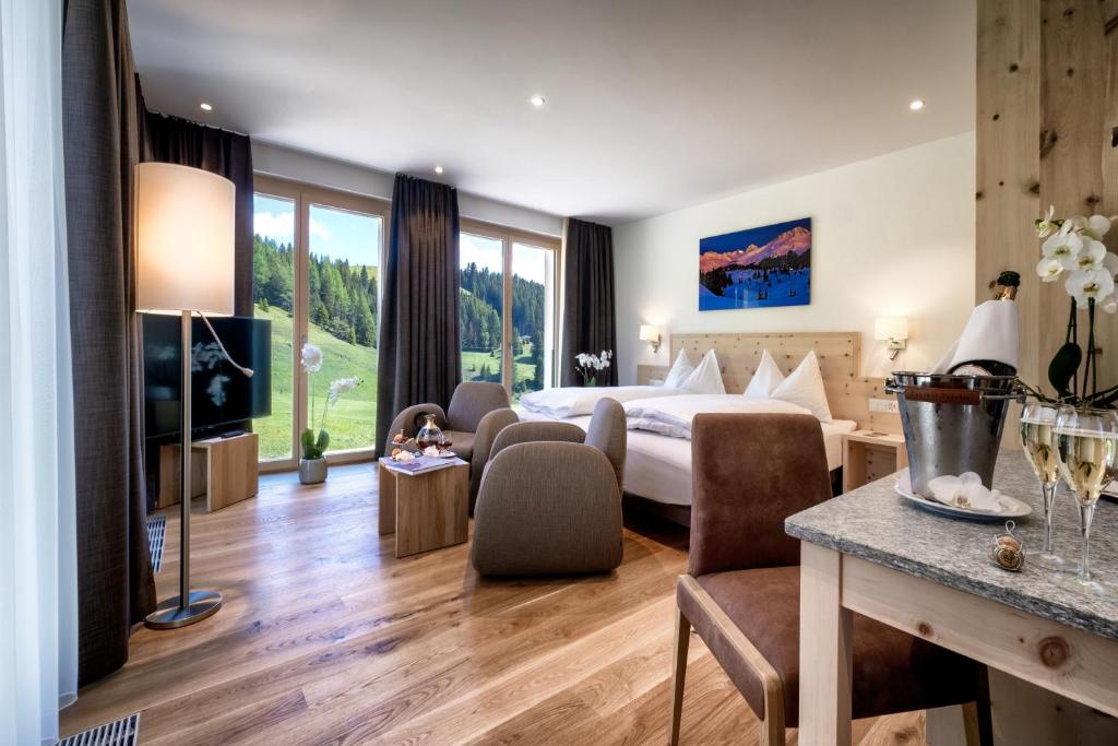 ein Hotelzimmer mit einem Bett, einem Tisch und Stühlen in der Unterkunft Golf- & Sporthotel Hof Maran in Arosa