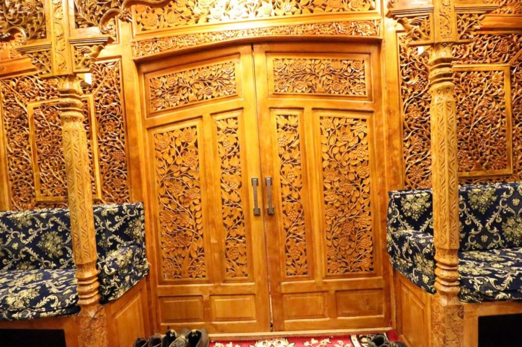 Cette chambre dispose d'une porte en bois avec 2 sièges. dans l'établissement Umbrella group of House Boat, à Srinagar