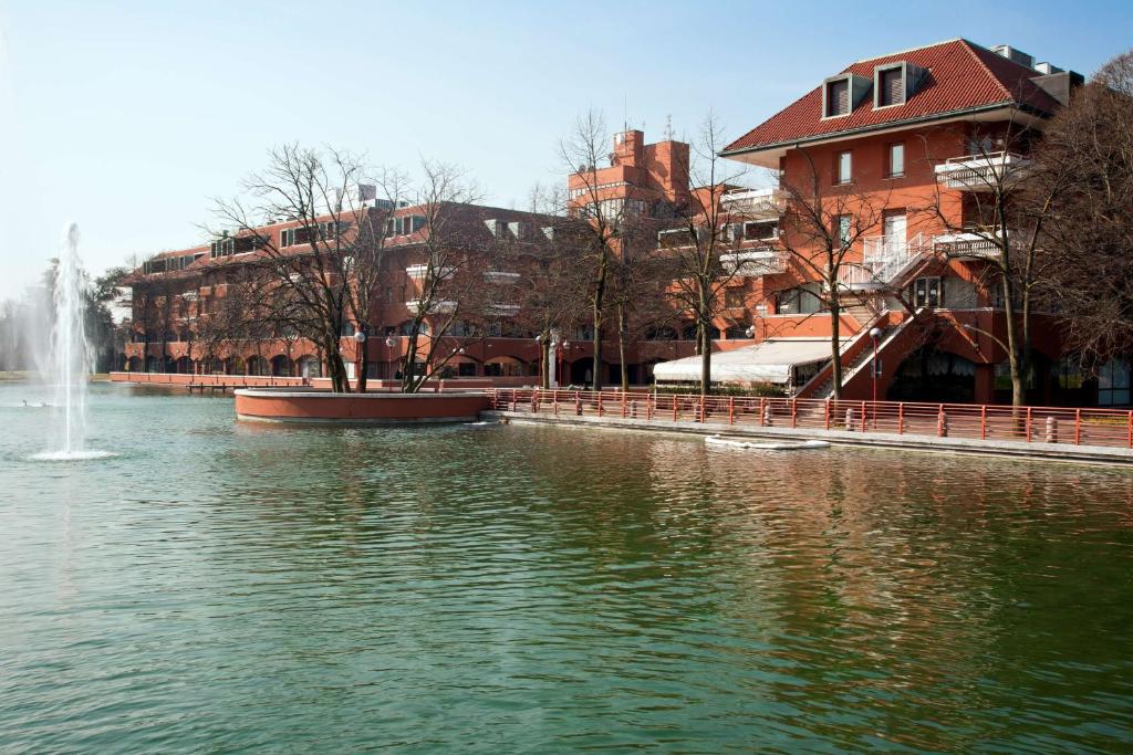 a fountain in the middle of a lake with buildings at NH Milano 2 Residence in Segrate