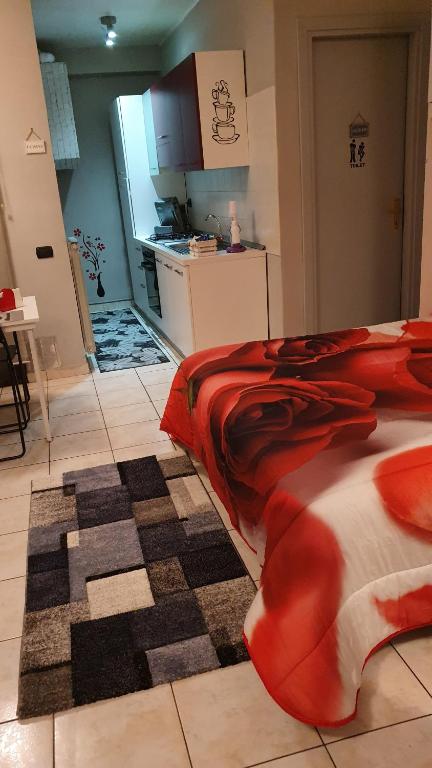 a bedroom with a red bed and a kitchen at Alloggio Turistico "FRANCESCA" in Viterbo