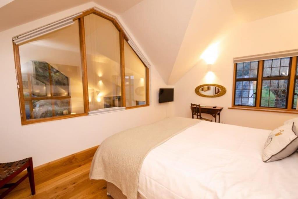 a bedroom with a white bed and two windows at Heron Place, Great Langdale in Ambleside