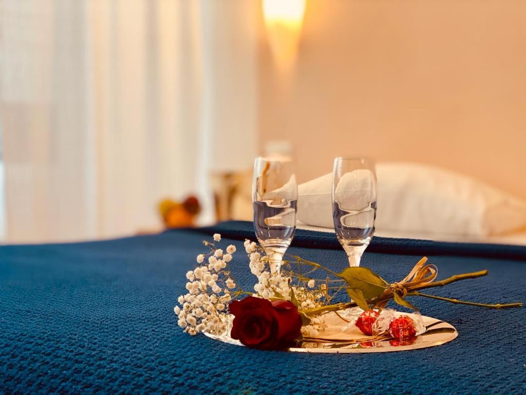 une assiette avec deux verres à vin et des fleurs sur une table dans l'établissement Le Suite Sul Corso, à Cagliari