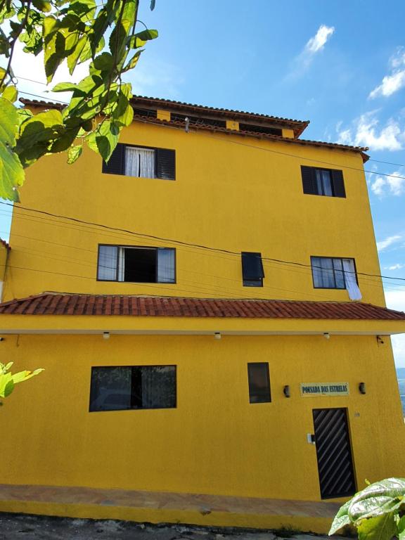 un edificio amarillo con techo rojo en Pousada das Estrelas, en São Thomé das Letras