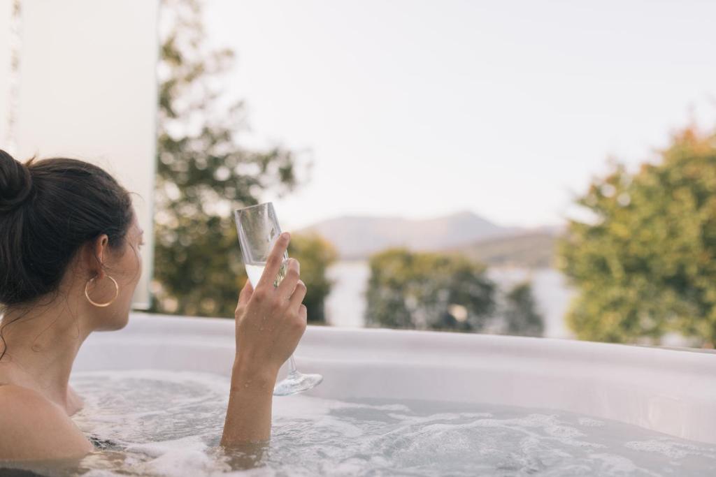 a woman holding a cell phone in front of a pool of water at SeaBeds - Luxury Lookouts with Hot Tubs in Fort William