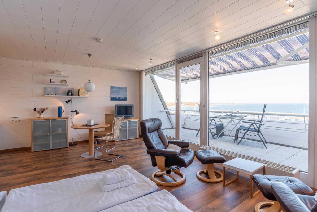 ein Wohnzimmer mit einem Bett und Stühlen sowie einem Balkon in der Unterkunft Ferienwohnung Hafen & Strand in Schilksee