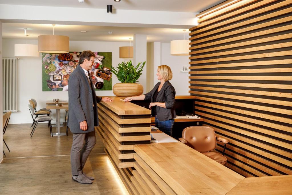 a man and a woman standing at a reception desk at Hotel am Peterstor in Regensburg