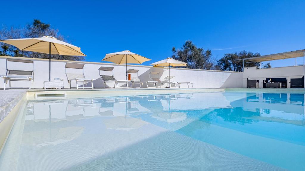 a swimming pool with chairs and umbrellas on a building at Villa Christelle Luxury Pescoluse by HDSalento in Marina di Pescoluse