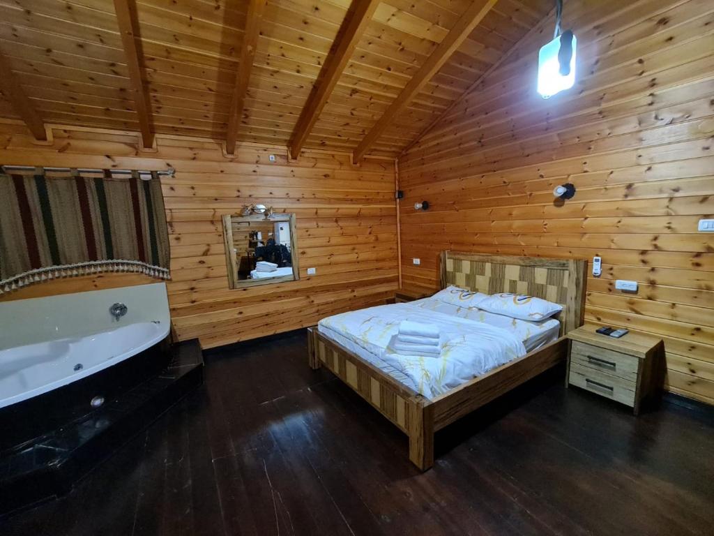 1 dormitorio con cama y bañera en una habitación de madera en בקתות היובל, en Kiryat Shemona