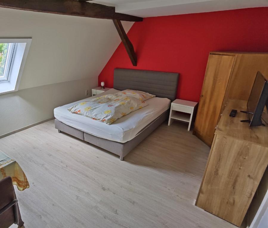 a bedroom with a bed and a red wall at Zum Schwarzen Adler in Mainberg