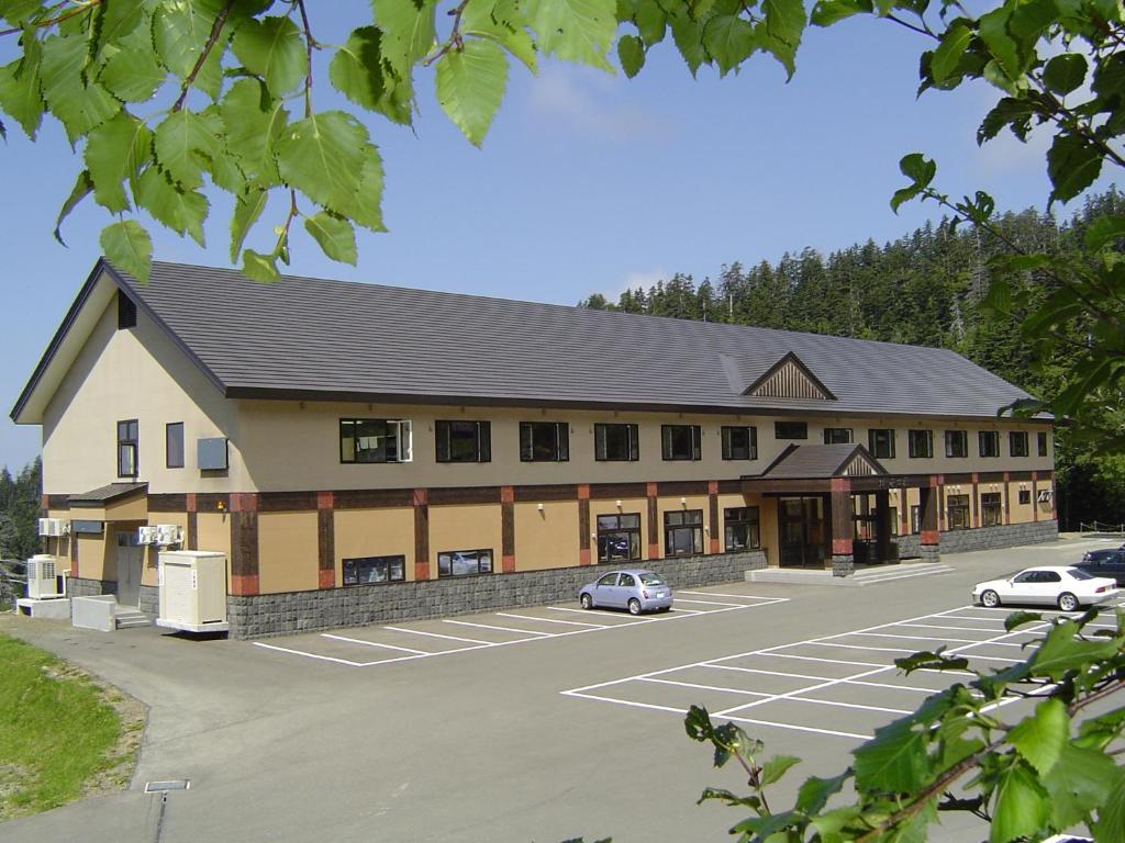 un grand bâtiment avec des voitures garées dans un parking dans l'établissement Kamihoroso, à Kami-furano