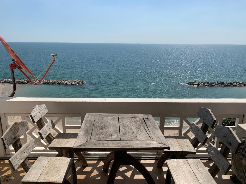 a wooden table and chairs on a balcony overlooking the ocean at Banchaitalay Room in Rayong