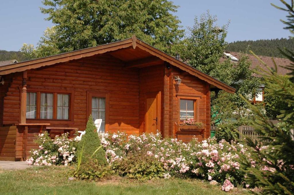 uma cabana de madeira com flores à frente em Ferienhaus Pöttgen em Arnsberg