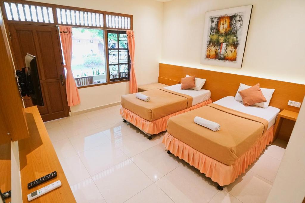 a room with two beds and a window at Sari Bali Cottage in Kuta