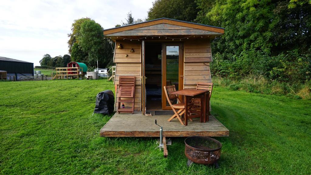 Cabaña pequeña con mesa y sillas en un campo en Unique Off- Grid Beehive Pod at Westcote Glamping, en Hawick