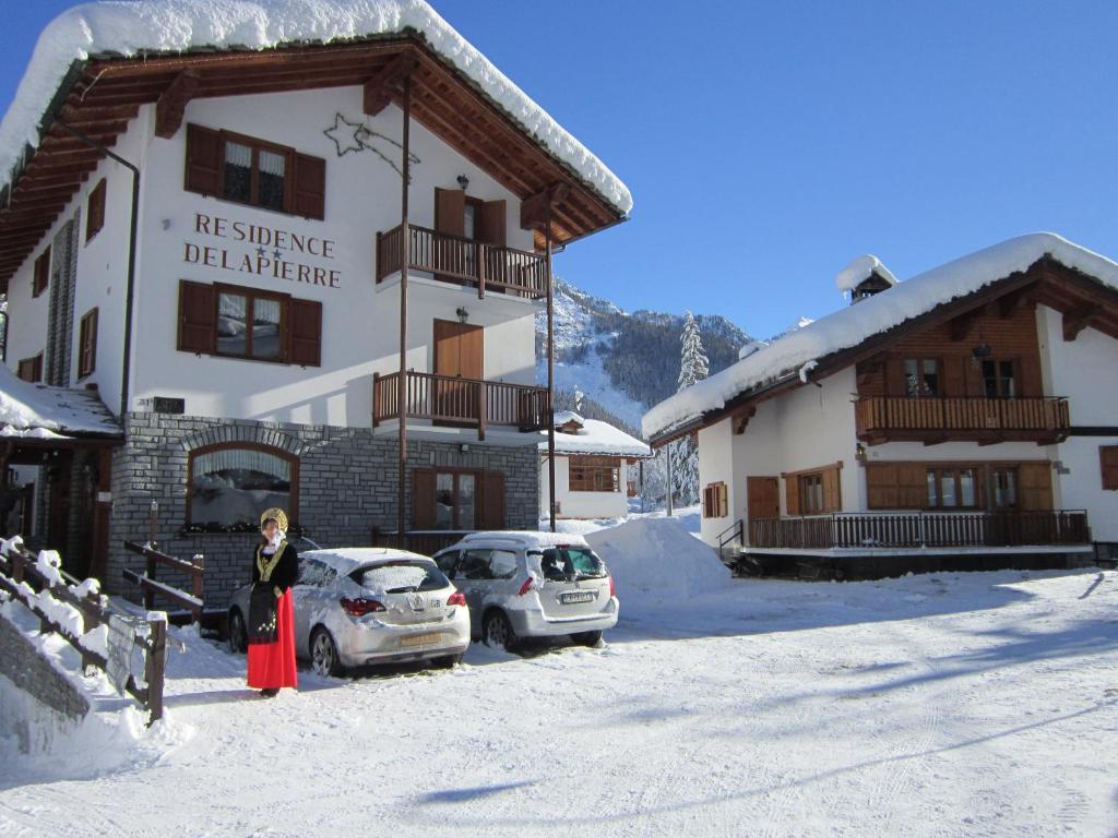 a woman standing in front of a building in the snow at Residence Delapierre in Gressoney-Saint-Jean