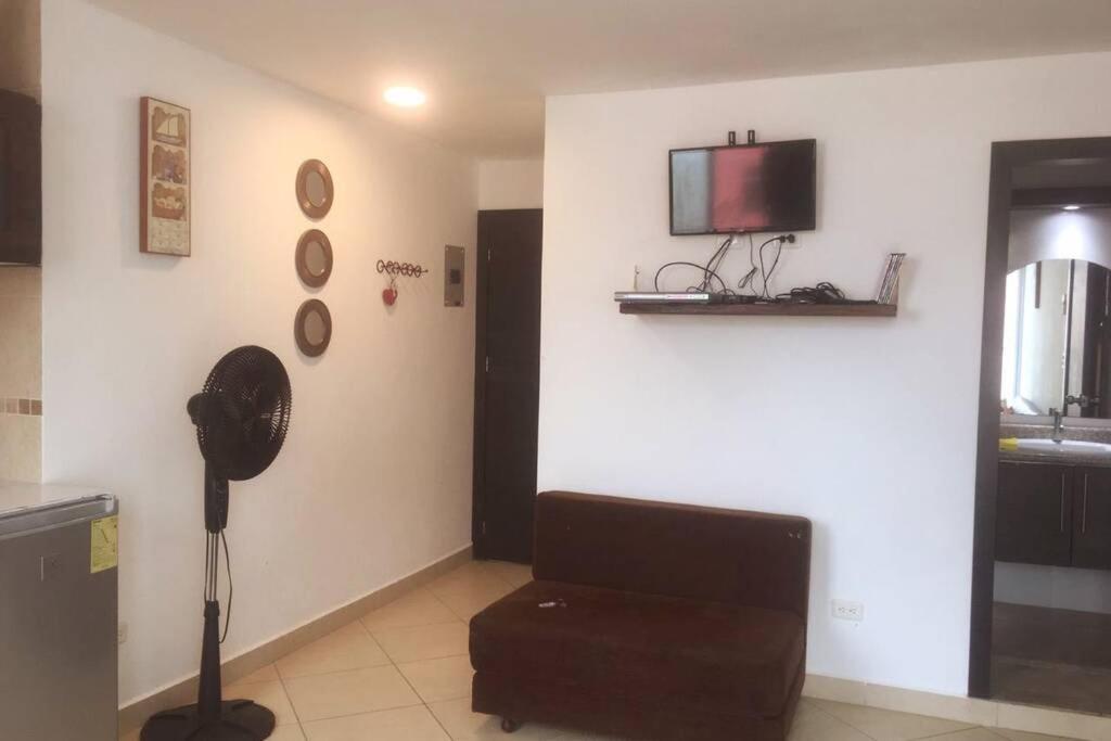 sala de estar con sofá y TV en la pared en Espectacular suite en malecón de Atacames, en Atacames