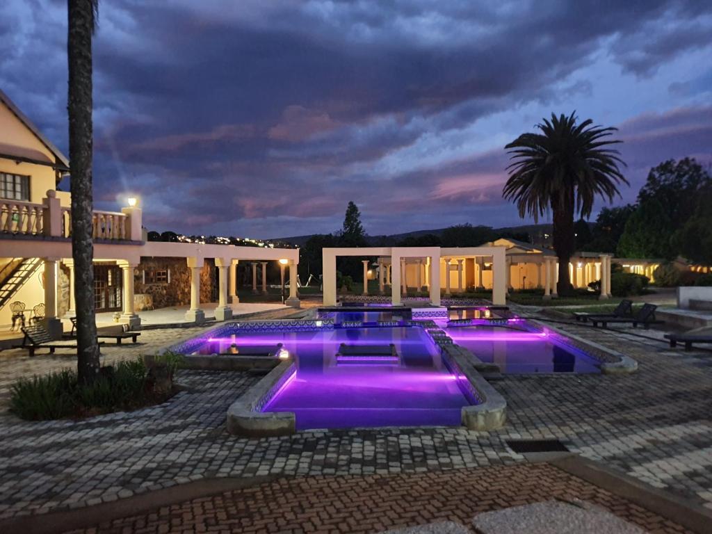 a courtyard with three pools with purple lights at Floreat Riverside Lodge and Spa in Sabie