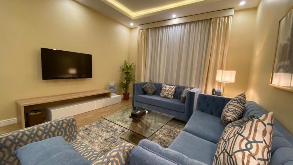 ماس للشقق الفندقية الفاخرة في جدة: غرفة معيشة مع أرائك زرقاء وتلفزيون بشاشة مسطحة