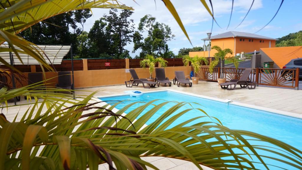 una piscina con sillas y un patio con una casa en Appartement d'une chambre a Deshaies a 900 m de la plage avec piscine partagee jardin clos et wifi en Deshaies