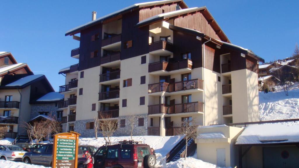 a building in the snow with cars parked in front of it at Studio avec balcon a Vallandry in Landry
