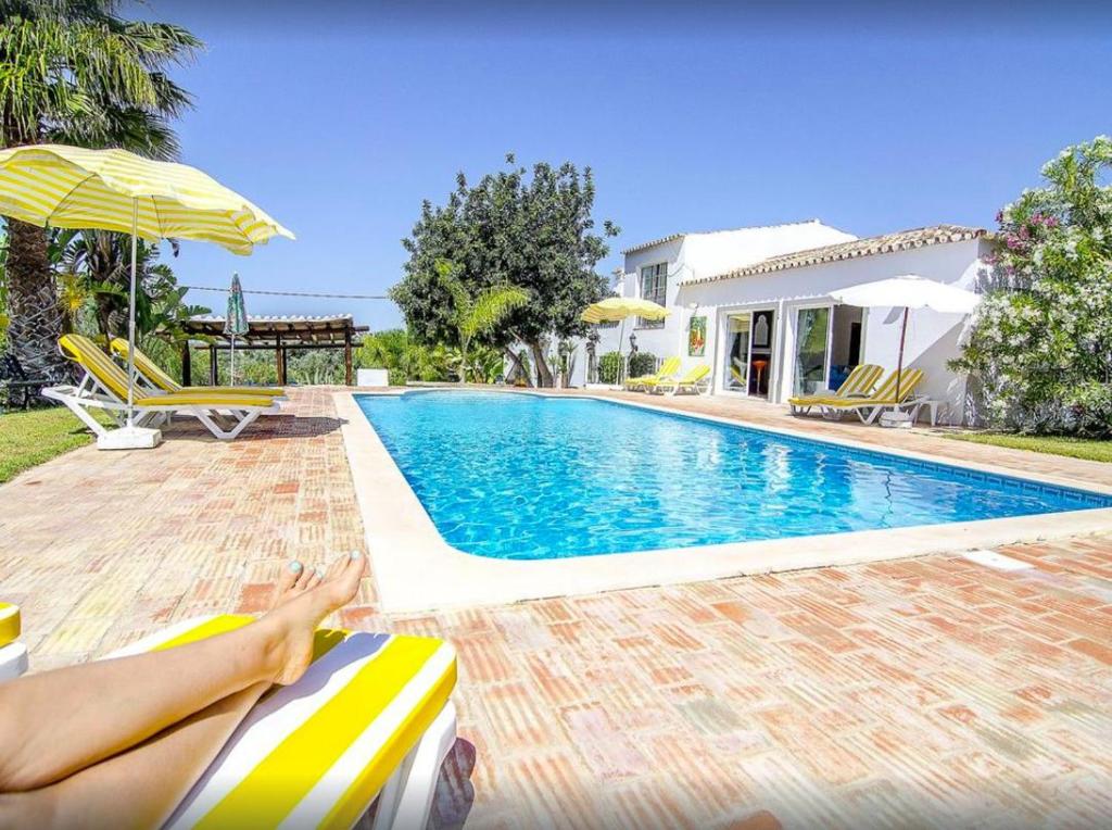 Eine Frau, die auf einem Stuhl neben einem Pool liegt. in der Unterkunft 6 bedrooms villa with sea view and private pool at Loule in Loulé