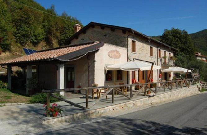 a building with tables and umbrellas next to a street at Agriturismo Spino Fiorito in Casola in Lunigiana