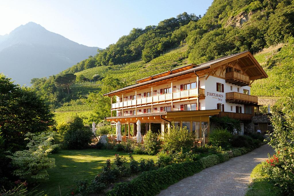 a building on a hill with a mountain at Hotel Garni Partaneshof in Merano