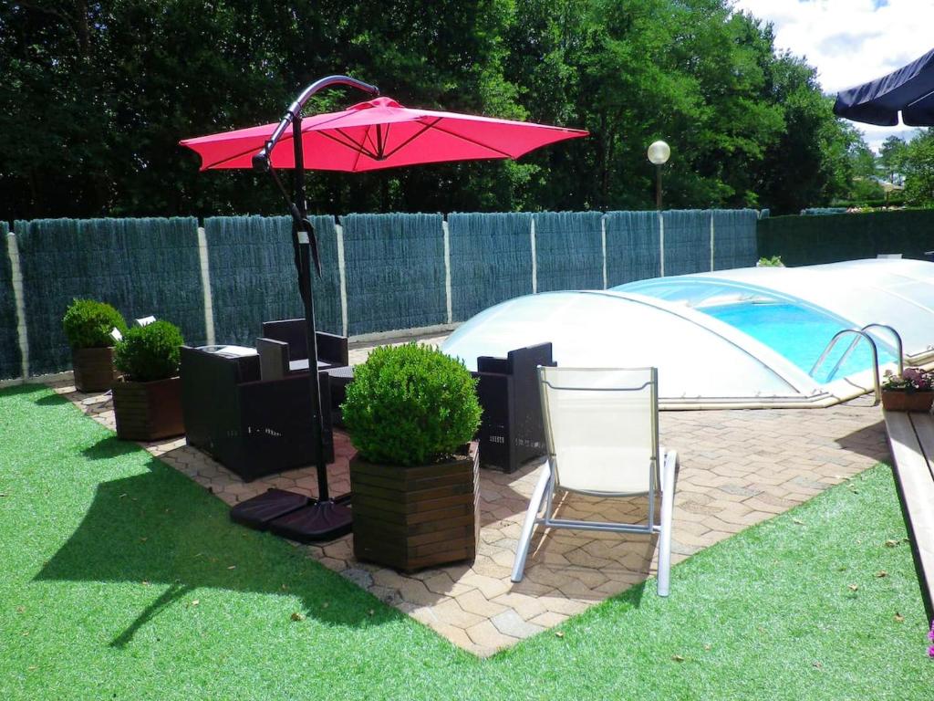 a pink umbrella and a chair in a yard at Villa en pleine nature à Escource avec piscine privée in Escource