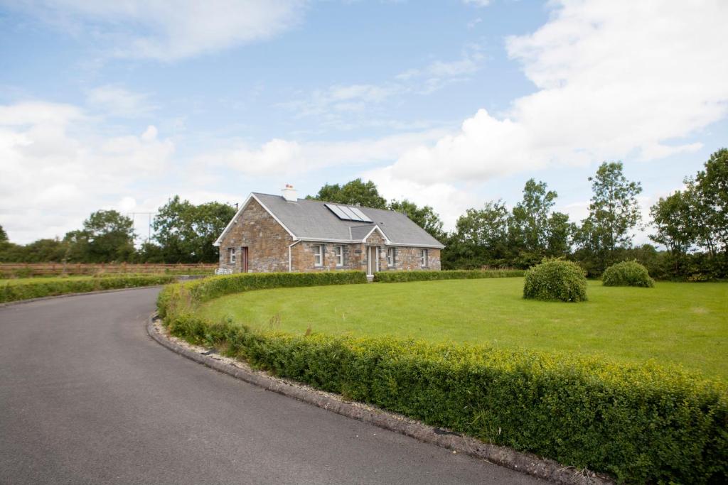 ein Haus auf einem Grasfeld neben einer Straße in der Unterkunft Inviting 4-Bed House in Strokestown in Grange