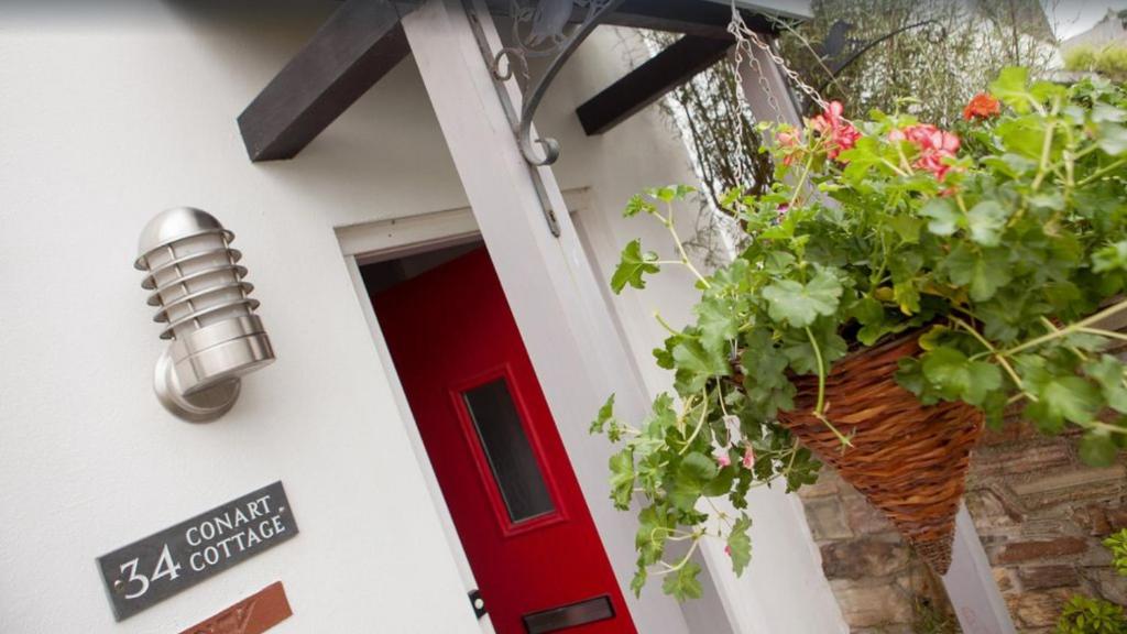 a house with a red door and a potted plant at Fabulous house very near Charlestown Harbour in Charlestown