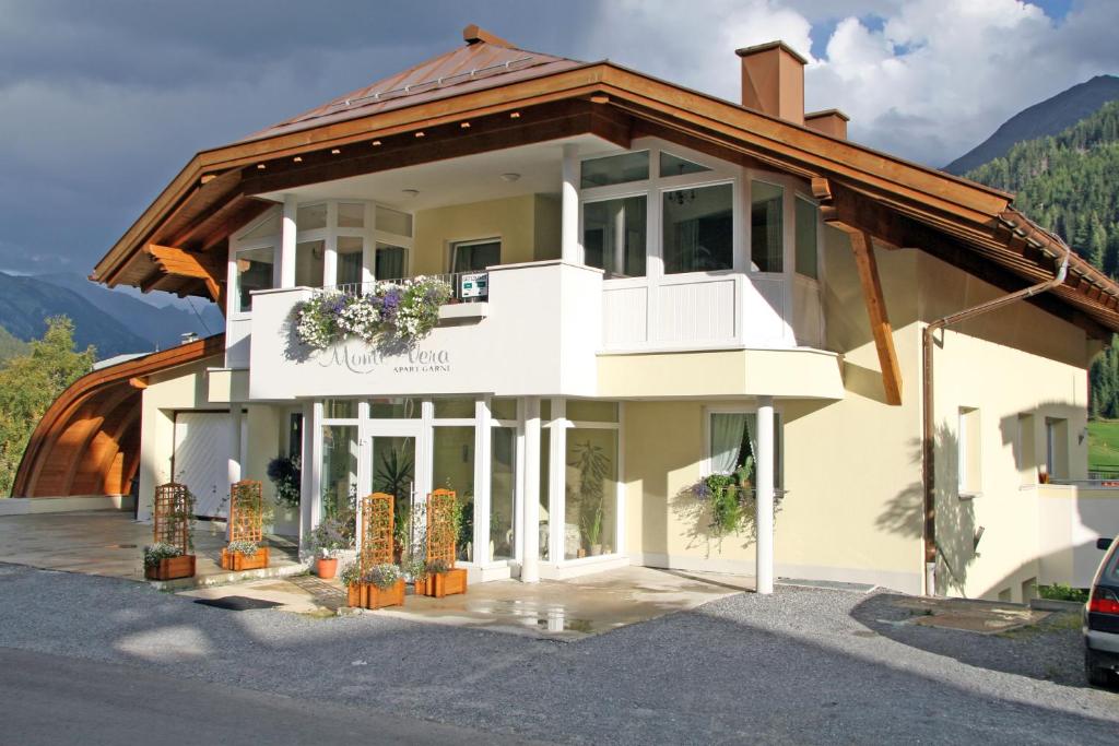 un gran edificio blanco con plantas en un estacionamiento en Apart Garni Monte Vera, en Sankt Anton am Arlberg