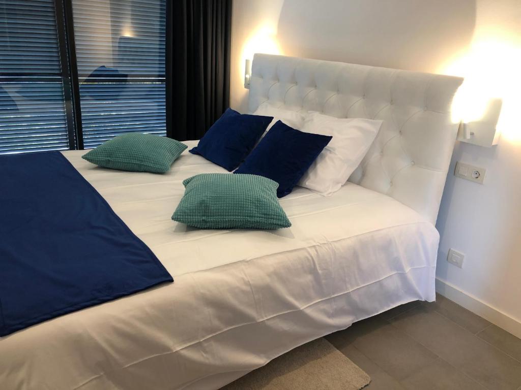 a large white bed with blue pillows on it at Splendide Villa les pieds dans l'eau dans la baie de Mahon in Es Castell