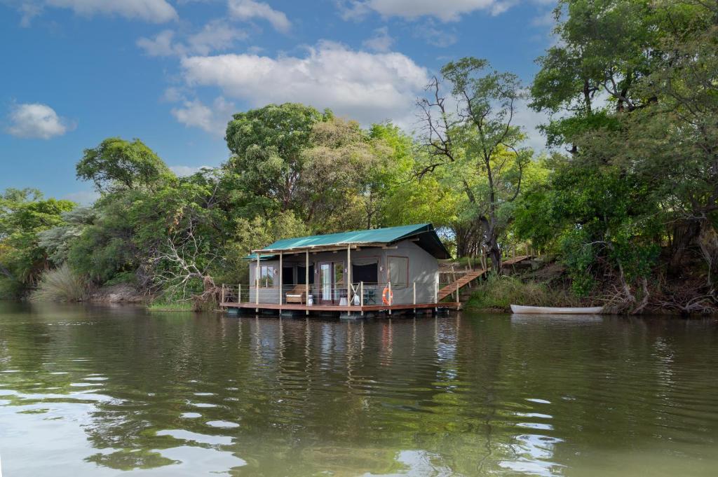 uma casa num barco num rio em Ndhovu Safari Lodge em Mahango