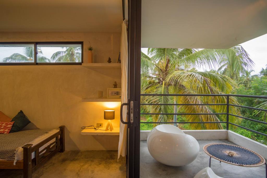 a room with a bed and a balcony with a window at Casa Chapolin Boutique Guesthouse in Palomino