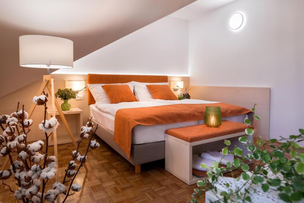 a bedroom with a bed with an orange bedspread at Hotel Gostilna Vovko in Novo Mesto