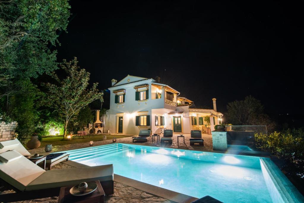 una piscina frente a una casa por la noche en Villa Magnolia Corfu, en Perama