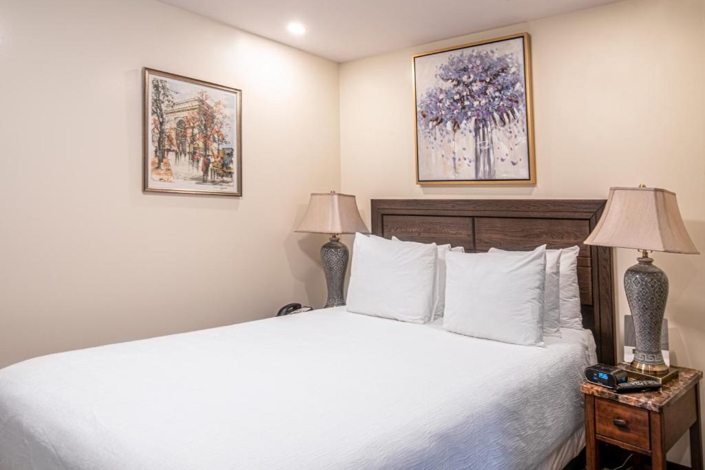 a bedroom with a large white bed with two lamps at The Business Inn in Ottawa